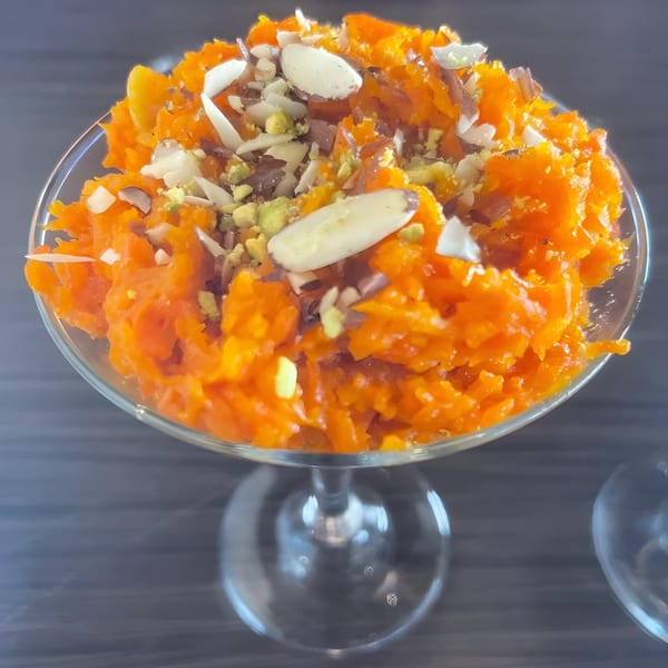 Pakwan Indian restaurant's Gajar Halwa dessert, a bright orange carrot pudding topped with nuts in a glass.