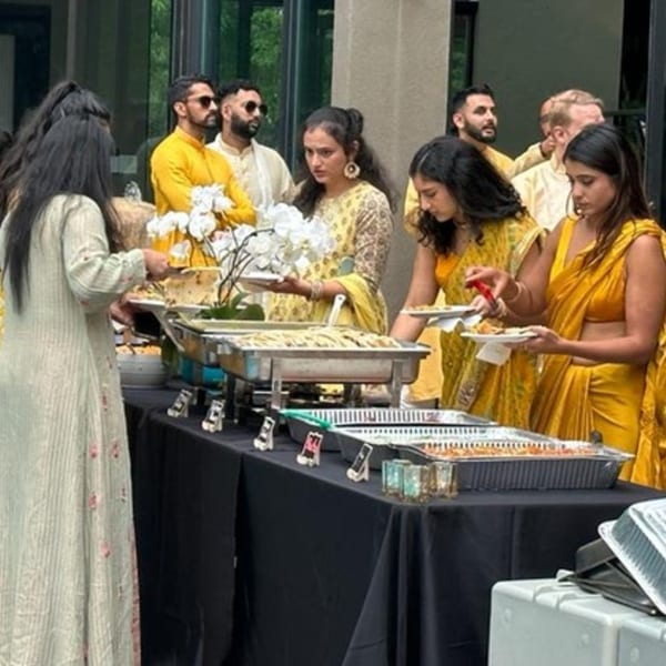 Guests in traditional Indian attire serving themselves from a buffet of Indian food at Pakwan restaurant.